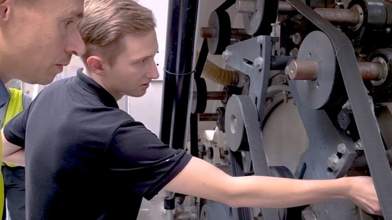 Zwei Männer beugen sich über eine Maschine.