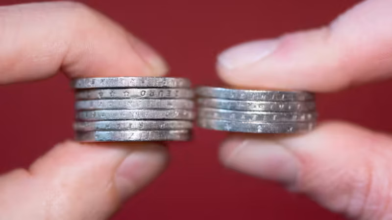 Ein Mann (links) und eine Frau in Dresden halten gestapelte Zwei-Euro-M&uuml;nzen zwischen Daumen und Zeigefinger. Die Lohnl&uuml;cke in Sachsen sinkt, aber nicht &uuml;berall gleich stark.
Quelle: Sebastian Kahnert/dpa