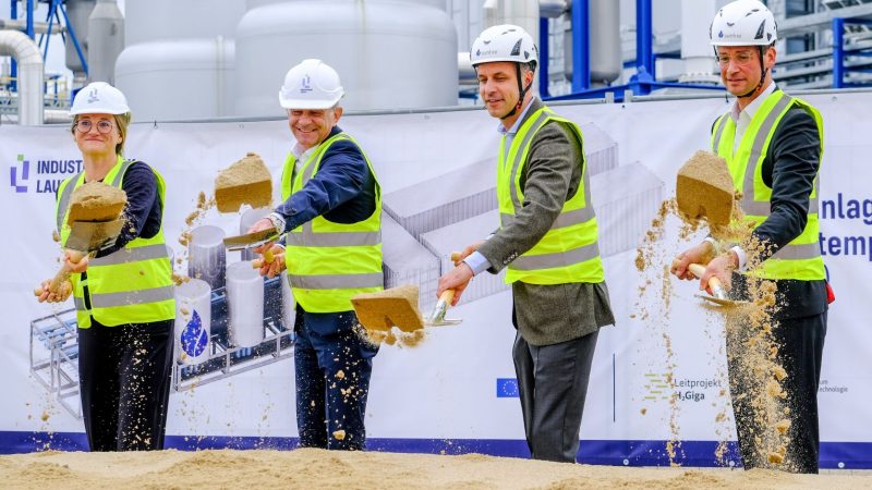 Vier Menschen schippen Sand