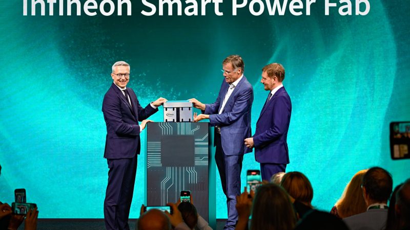 Drei M&auml;nner stehen unter dem Schriftzug Infineon Smart Power Fab